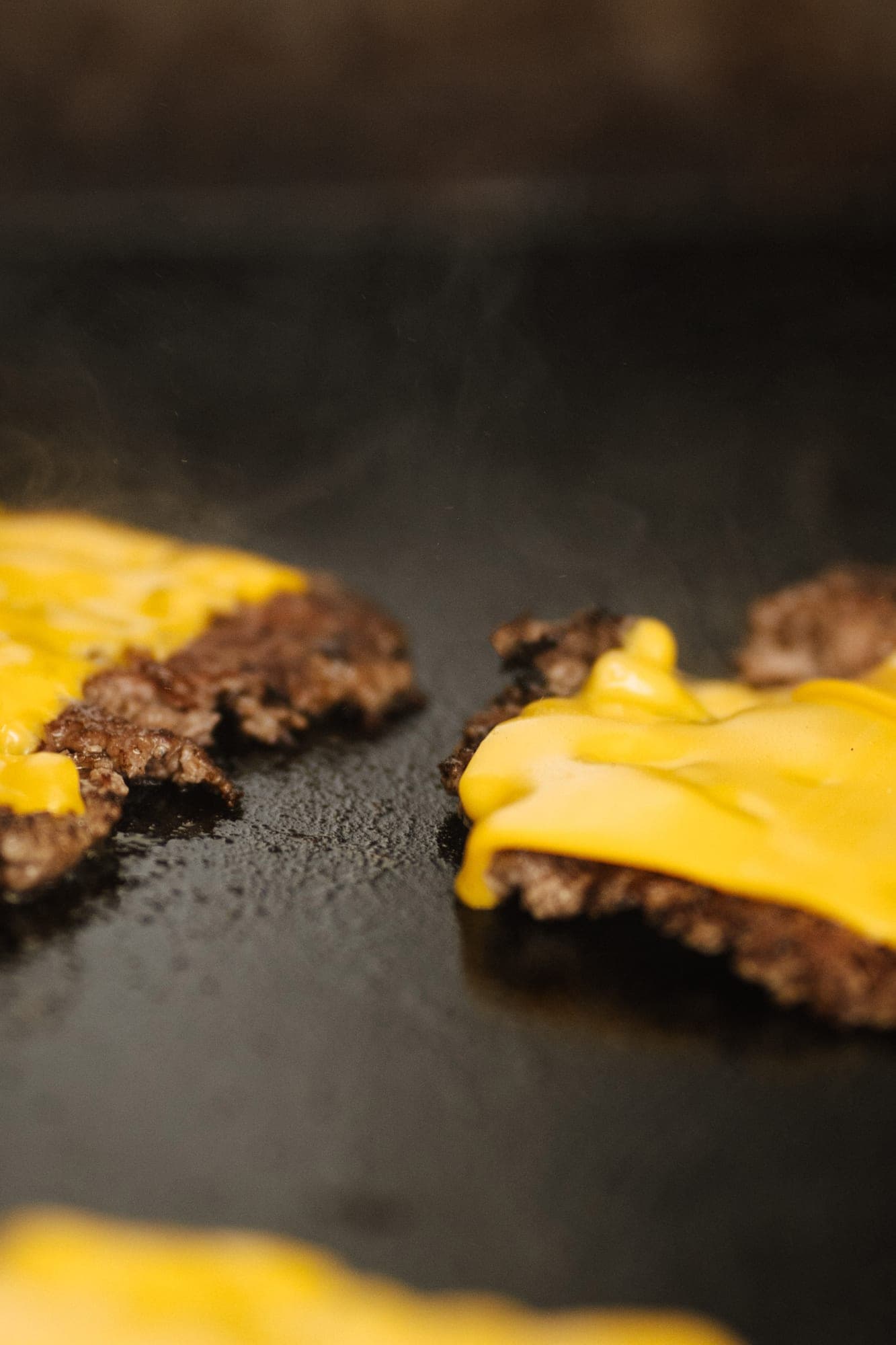 Olvadó american cheese a smashelt húspogácsákon a forró lapon
